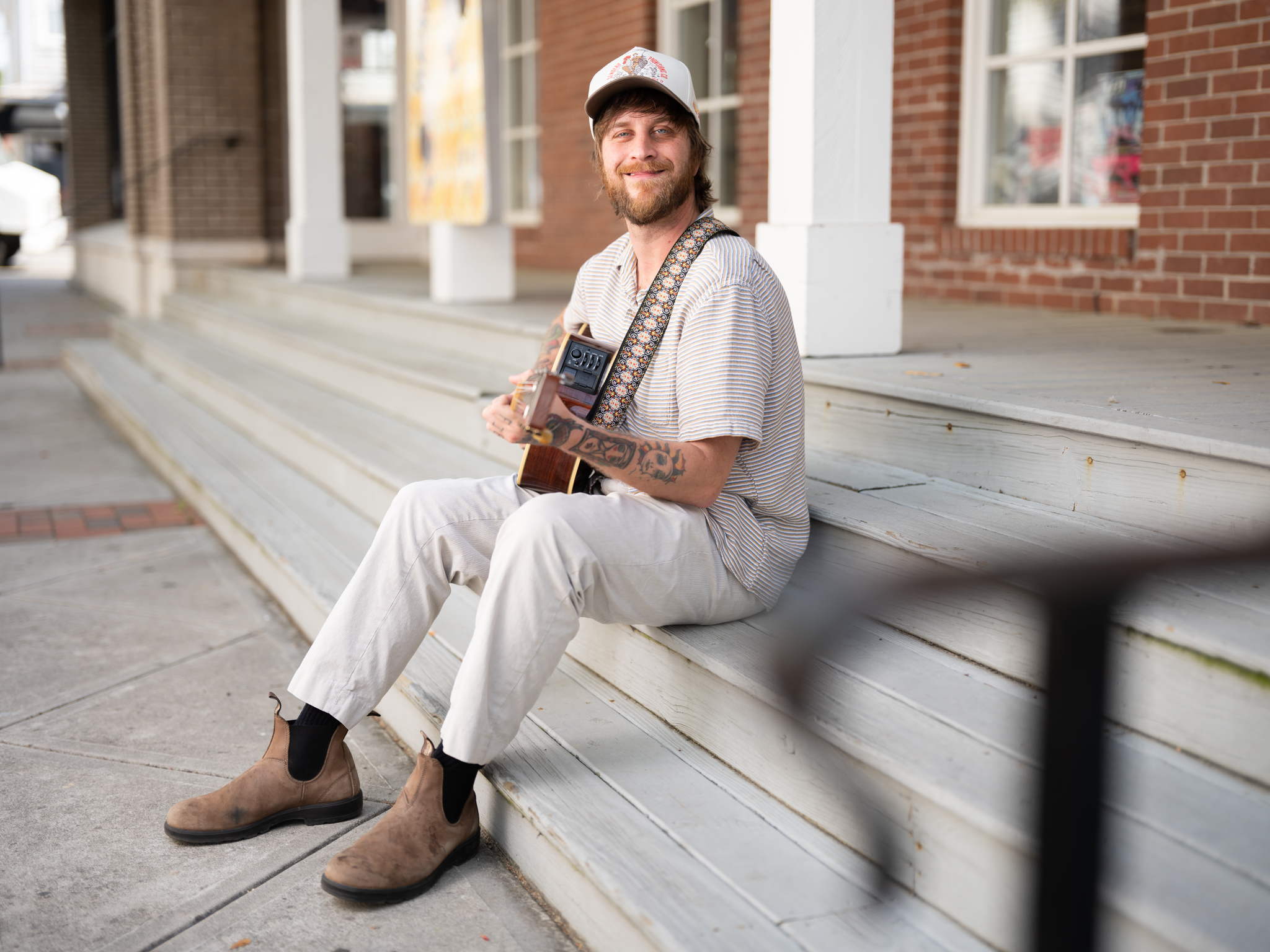 Tyler Littlejohn sitting on steps playing a guitar